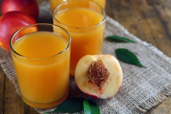 Mogna persikor och glas saft på trä bakgrund — Stockfoto