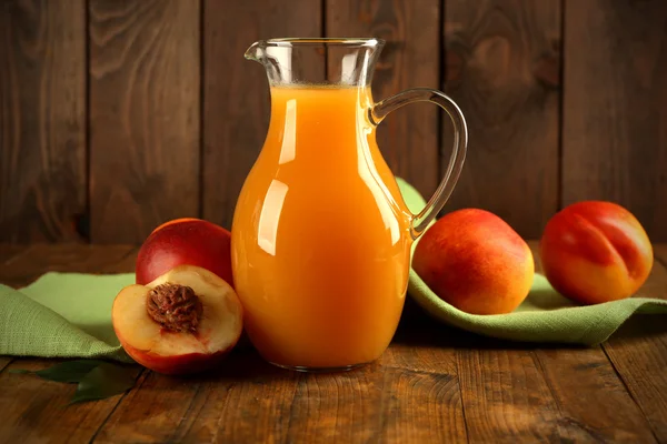 Persikojuice och mogna persikor på trä bakgrund — Stockfoto