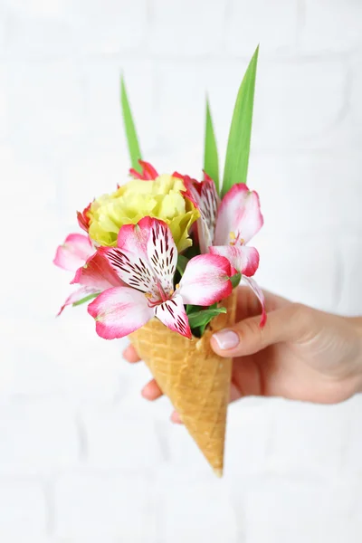 Kvinnans hand som håller vilda blommor i rånet på ljus vägg bakgrund — Stockfoto