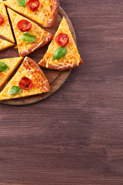 Scheiben leckere Käse-Pizza mit Basilikum und Kirschtomaten auf dem Tisch aus nächster Nähe — Stockfoto