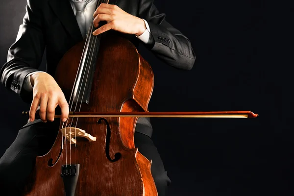 Чоловік грає на віолончелі на темному фоні — стокове фото