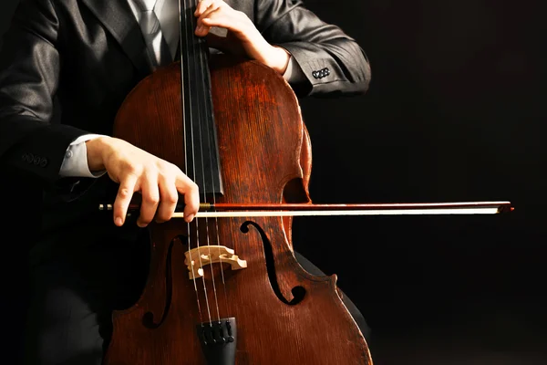 Homme jouant sur violoncelle sur fond sombre — Photo