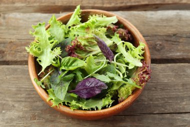 Ahşap masa üzerinde kase taze karışık yeşil salata yakın çekim