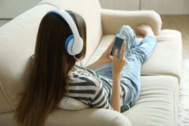 Kadın odada kulaklıkla müzik dinliyor.