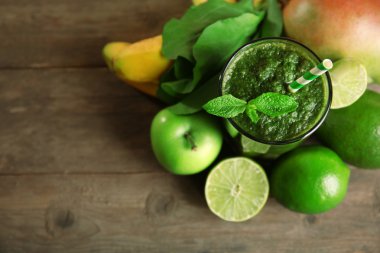 Yeşil sağlıklı suyu meyve ve ahşap masa üzerinde otlar ile yakın çekim