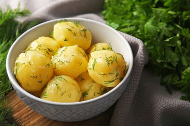 Boiled potatoes with greens in bowl on table close up clipart