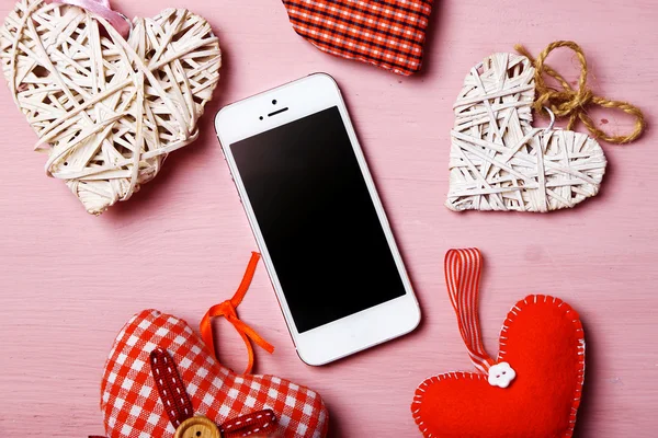 White smart phone with hearts on wooden desk. — Stock Photo, Image