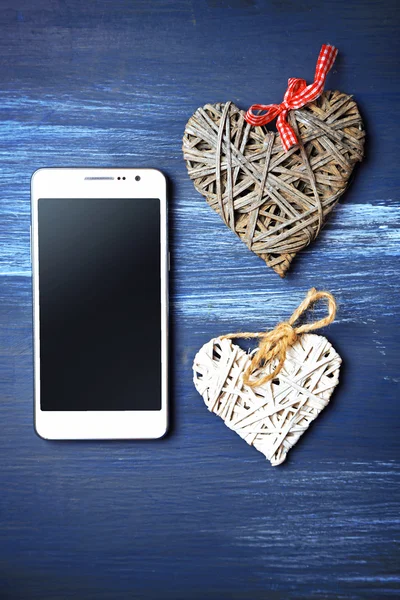 Bílý chytrý telefon s srdce na dřevěný stůl. — Stock fotografie
