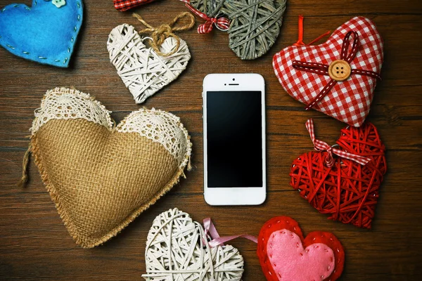 White smart phone with hearts on wooden desk. — Stock Photo, Image