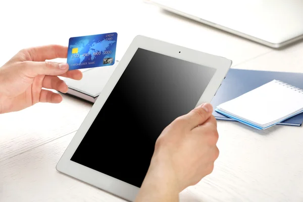 Man holding credit card and tablet on workplace background — Stock Photo, Image