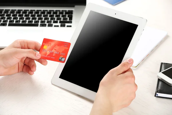 Man holding credit card and tablet on workplace background — Stock Photo, Image