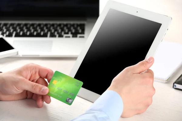 Homem segurando cartão de crédito e tablet no ambiente de trabalho — Fotografia de Stock