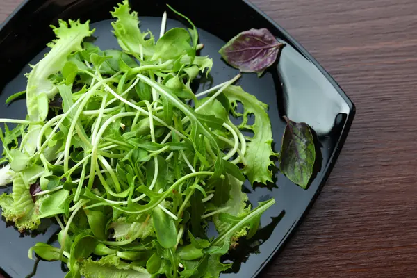 Плита свіжого змішаного зеленого салату на дерев'яному столі крупним планом — стокове фото