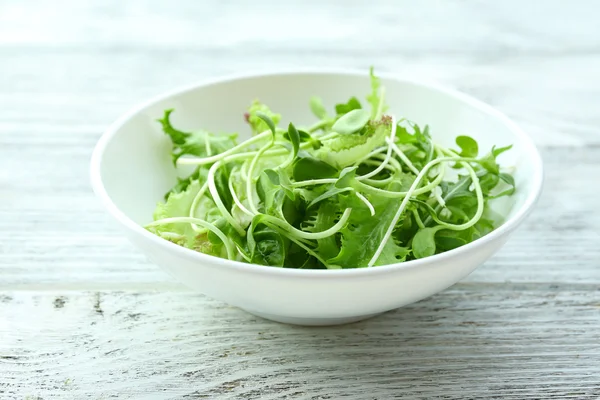 Frischer gemischter grüner Salat in Schüssel auf Holztisch in Großaufnahme — Stockfoto