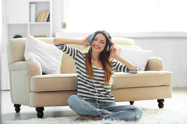 Mujer escuchando música en auriculares en la habitación —  Fotos de Stock