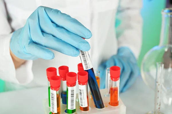 Test tubes with colorful liquid in scientist hand, closeup — Stock Photo, Image