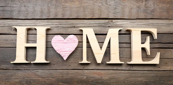 Letras decorativas formando palabra HOME con corazón sobre fondo de madera — Foto de Stock