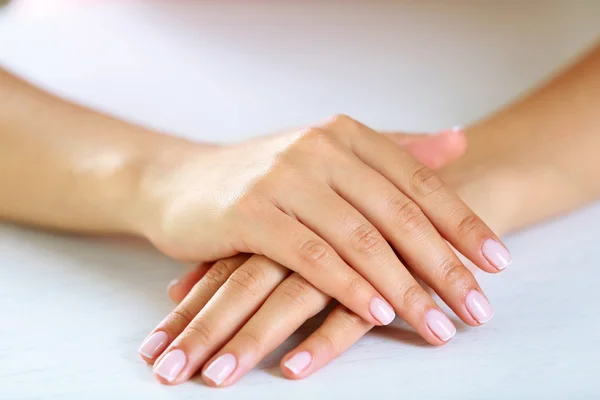 Frauenhände mit französischer Maniküre auf dem Tisch in Großaufnahme — Stockfoto