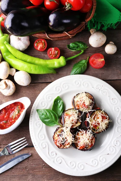 Plato de berenjena con tomates cherry y queso en plato blanco sobre mesa de madera, vista superior — Foto de Stock