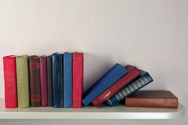 Livros antigos na prateleira, close-up, no fundo da parede de luz — Fotografia de Stock