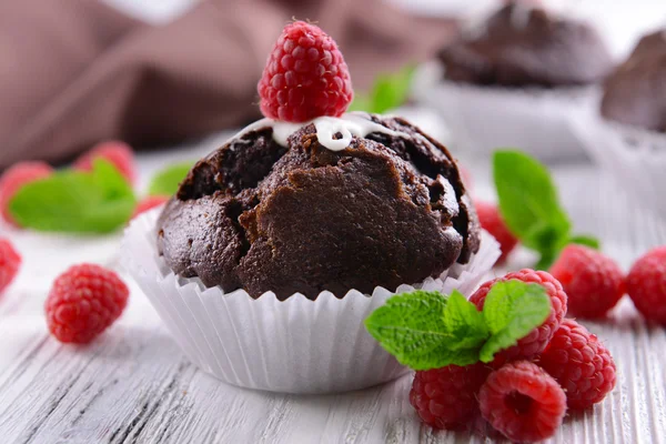 Delicious chocolate cupcake with berries on wooden table close up — Stock Photo, Image