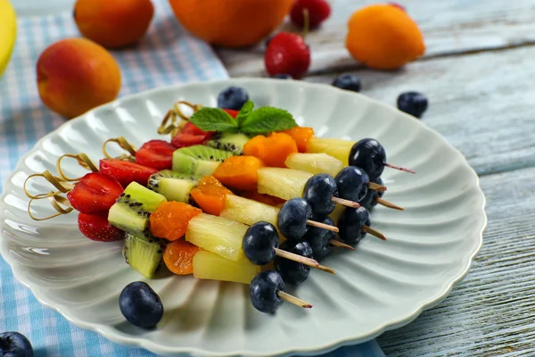Frutos frescos em espetos em prato na mesa, close-up — Fotografia de Stock