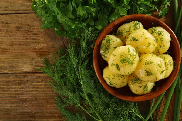 Вареный картофель с зеленью в миске на столе вблизи — стоковое фото