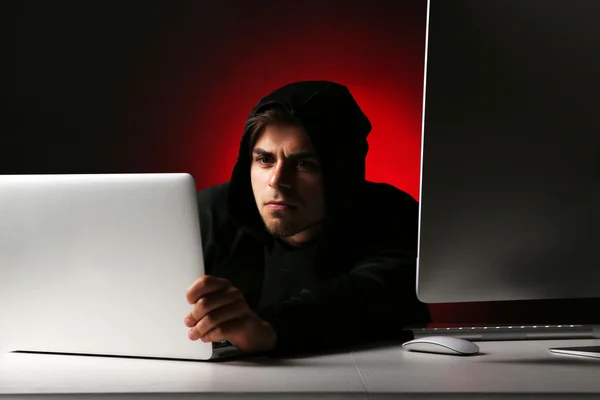 Hacker com computador e laptop no fundo escuro — Fotografia de Stock