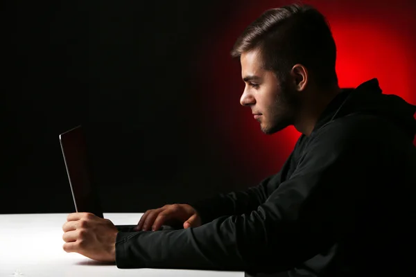 Hacker with computer and laptop on colorful dark background — Stock Photo, Image