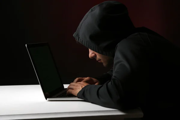 Hacker com computador e laptop sobre fundo escuro colorido — Fotografia de Stock