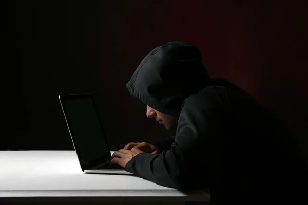 Хакер с компьютером и ноутбуком на красочном темном фоне — стоковое фото