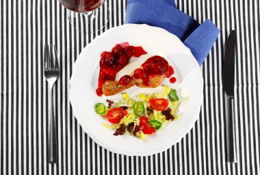 Tabak pişmiş tavuk budu ve kadeh şarap peçete, üstten görünüm tablo ile beyaz tabakta sebze salatası