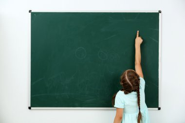 Küçük kız sınıfta Siyah Kara tahta bir şeye işaret