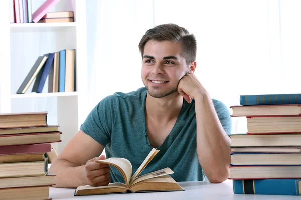 Jonge man leesboek aan tafel op kamer — Stockfoto
