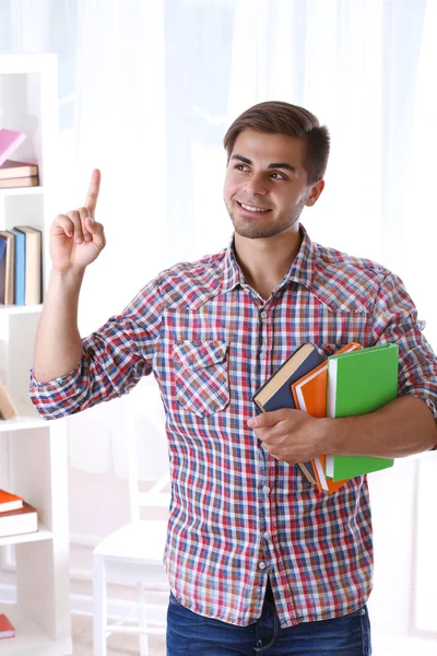 Joven con libros en la habitación — Foto de Stock