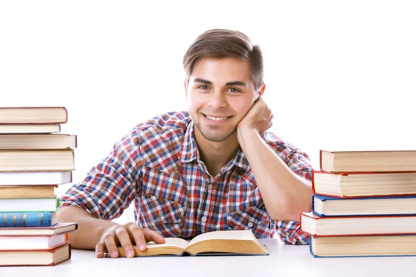 Junger Mann liest Buch am Tisch auf weißem Hintergrund — Stockfoto