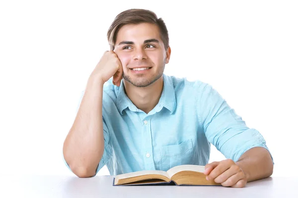 Joven leyendo libro en la mesa sobre fondo blanco — Foto de Stock