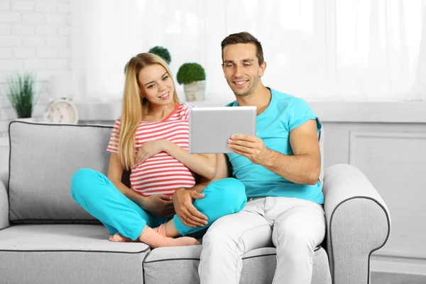 Young pregnant woman with husband on sofa in room — Stock Photo, Image