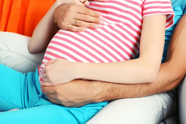 Young pregnant woman with husband on sofa in room — Stock Photo, Image