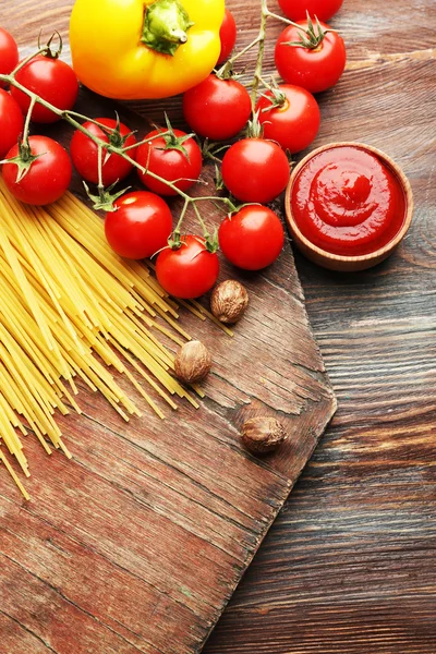 Espaguetis de pasta con tomates, queso y albahaca sobre fondo rústico de madera —  Fotos de Stock