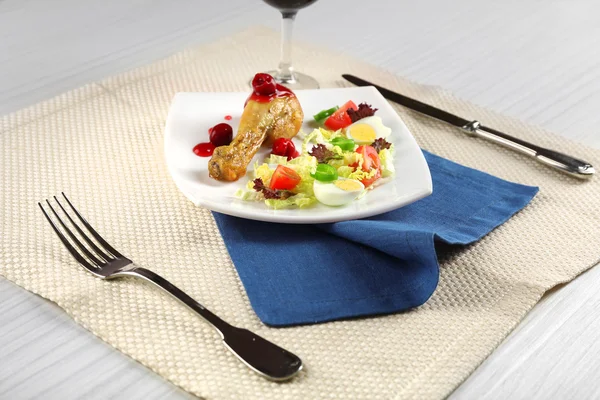 Danie z kurczaka pieczone nogi i warzyw sałatka w białej płytce przy lampce wina na stole z serwetka, zbliżenie — Zdjęcie stockowe