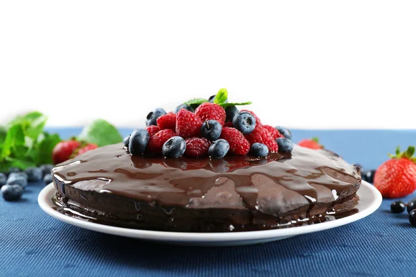 Heerlijke chocolade cake met zomer bessen op blauwe tafellaken, close-up — Stockfoto