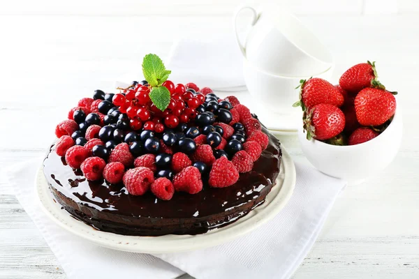 Delicious chocolate cake with summer berries on wooden table, closeup — Stock Photo, Image