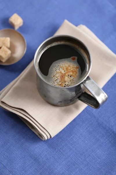 Tasse en métal de café aromatisé avec sucre en morceaux et fleurs sur la table avec serviette, gros plan — Photo