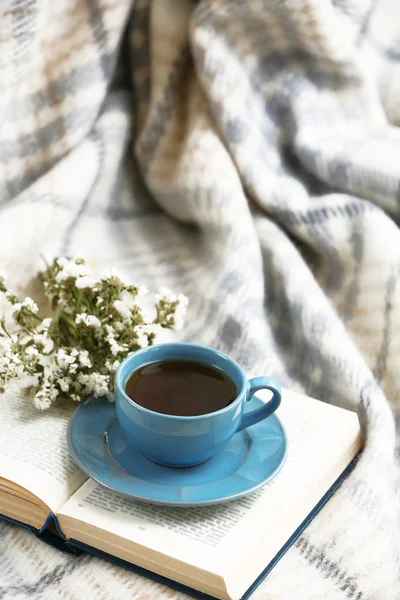 Blaue Tasse Kaffee mit offenem Buch auf Sofa im Zimmer — Stockfoto