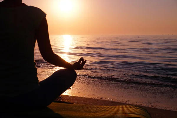 Genç sağlıklı kadın gün batımında plajda yoga yapıyor. — Stok fotoğraf