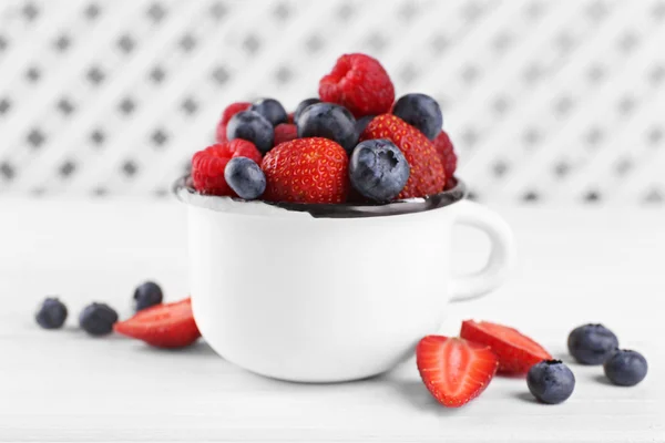 Leckere reife Beeren in Tasse auf Holztisch aus nächster Nähe — Stockfoto