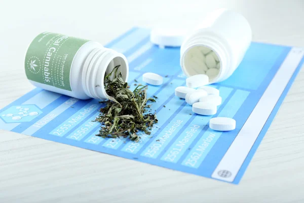 Flessen van droge medische cannabis en pillen op tafel close-up — Stockfoto