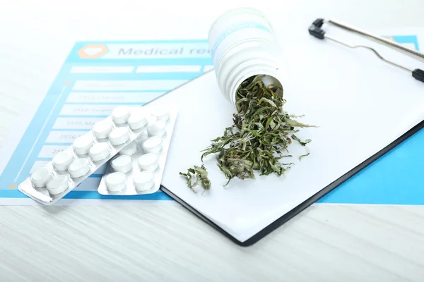 Пляшка сухого медичного канабісу і таблеток з буфера на столі крупним планом — стокове фото