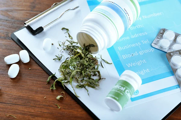 Botella de cannabis medicinal seco y pastillas con portapapeles en la mesa de cerca — Foto de Stock